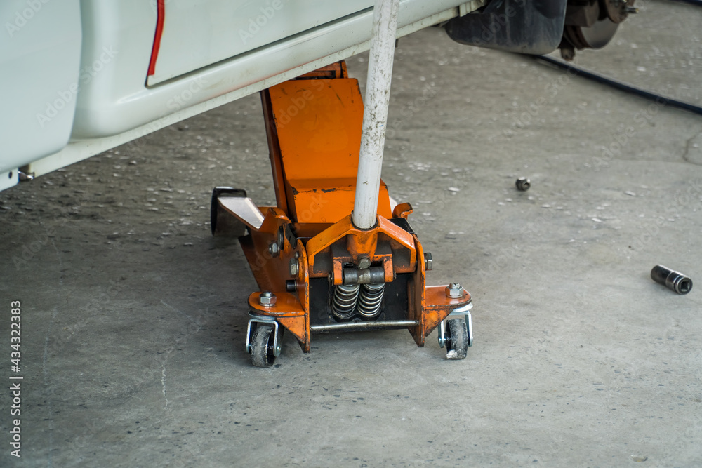 Car Lifted With Orange Hydraulic Floor Jack For Repairing or Change tire