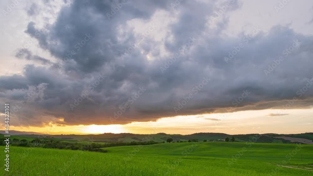 Time lapse: epic dramatic sky at sunset, unique landscape in Orcia Valley, Tuscany, Italy. Scenic clouds moving by storm wind. Sunset light over cultivated hill range and cereal crop fields. Time lapse: epic dramatic sky at sunset, unique landscape in Orcia Valley, Tuscany, Italy. Scenic clouds moving by storm wind. Sunset light over cultivated hill range and cereal crop fields.