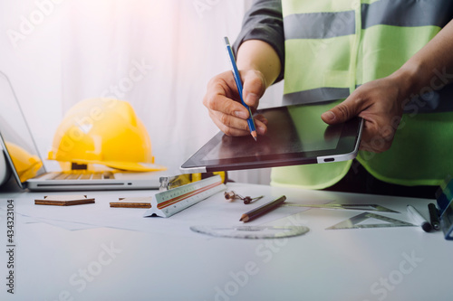 engineer working at a drawings of house in office for discussing. Engineering tools and construction concept.