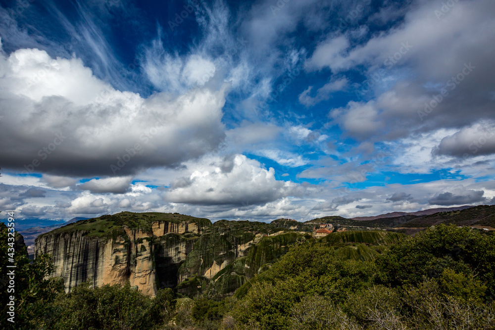 Moving huge white clouds scape seen from the beautiful green cliffs near the monasteries of Meteora, Greece, famous religious, Orthodox Christian, travel destination. 