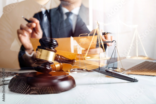 Business and lawyers discussing contract papers with brass scale on desk in office. Law, legal services, advice, justice and law concept picture with film grain effect