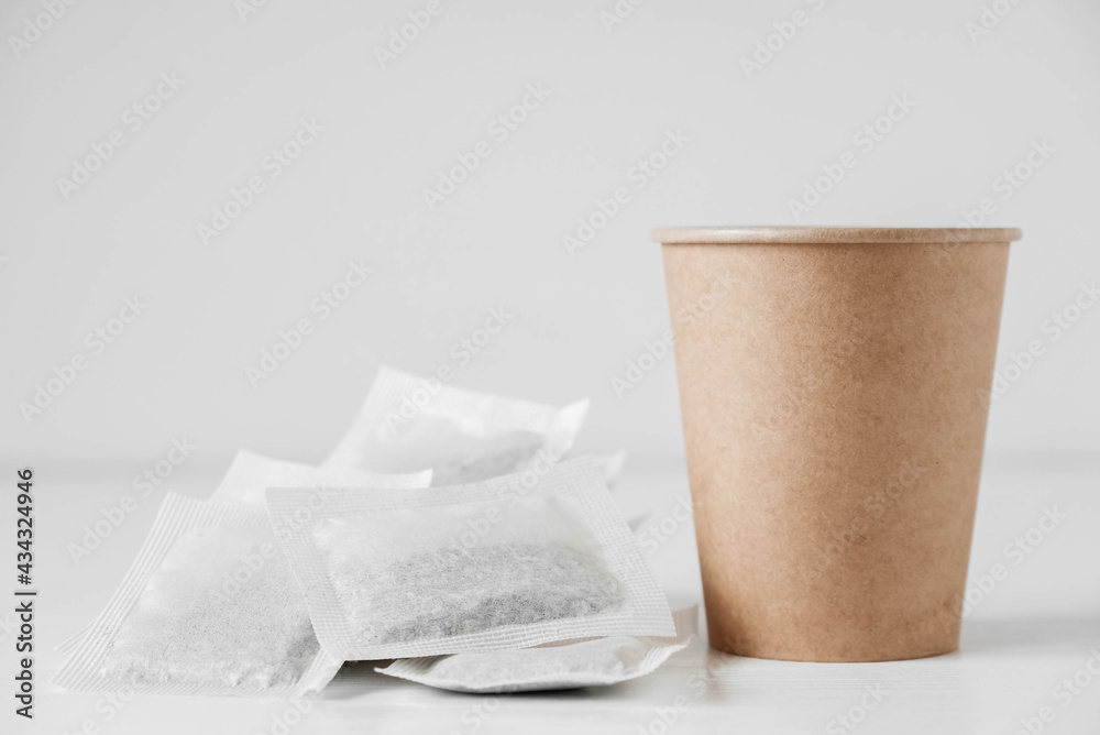 Paper cup and bags with tea on a white background. Copy, empty space for text Paper cup and bags with tea on a white background. Copy, empty space for text