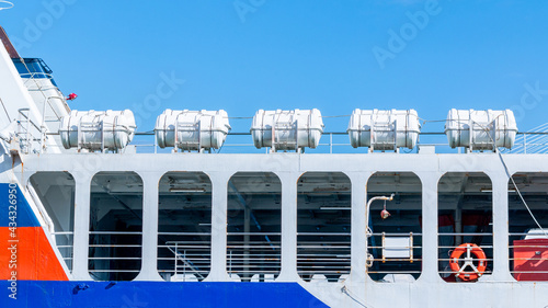 A group of inflatable liferafts arranged in a row on the upper deck of a cruise ship.