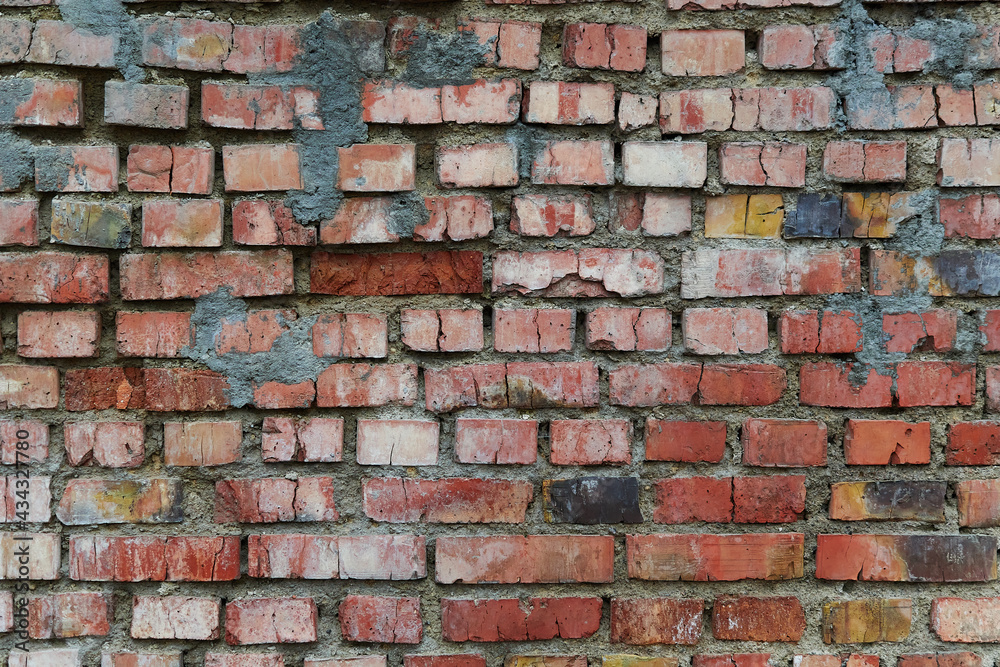 Old and broken brick, a sample of a brick wall in various shades of red, gray, orange and beige, sometimes covered with greenish mold. Wall texture and background for vintage wallpaper. Old and broken brick, a sample of a brick wall in various shades of red, gray, orange and beige, sometimes covered with greenish mold. Wall texture and background for vintage wallpaper.