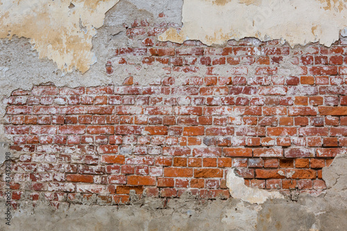 Old red brick wall background with peeling plaster. Grunge brickwall texture with stucco. Empty abstract stonewall backdrop with paint and plasterwork. Aged orange masonry with copy space