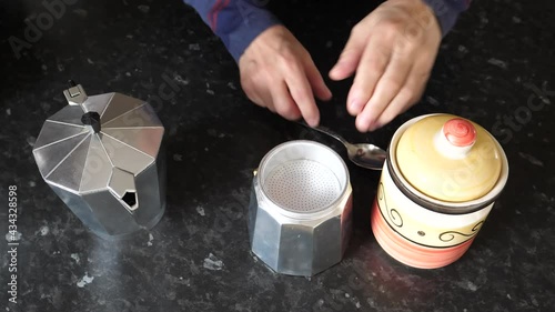 High angle view of hands of man preparing moka pot, Italian style stove top percolator for coffee brewing.