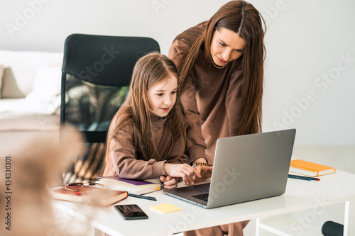 Mother and daughter are doing homework at the laptop © Andrii 