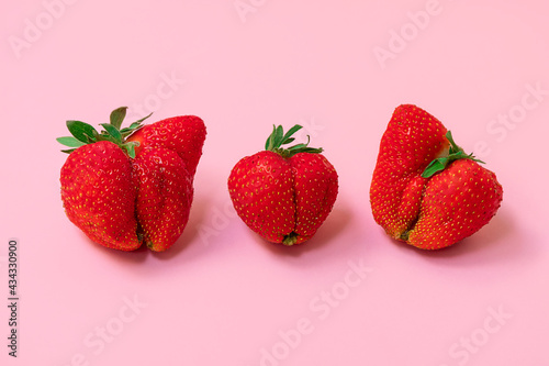 Large ugly strawberries on soft pink background. Ugly food concept
