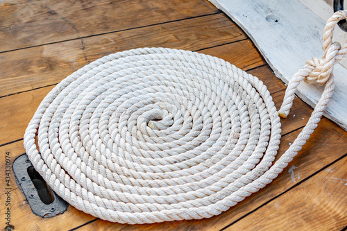 Mooring rope rolled into roll rings on a wooden board of an old boat.