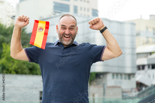 Cheerful middle aged man in the flag of Spain. Football fan.