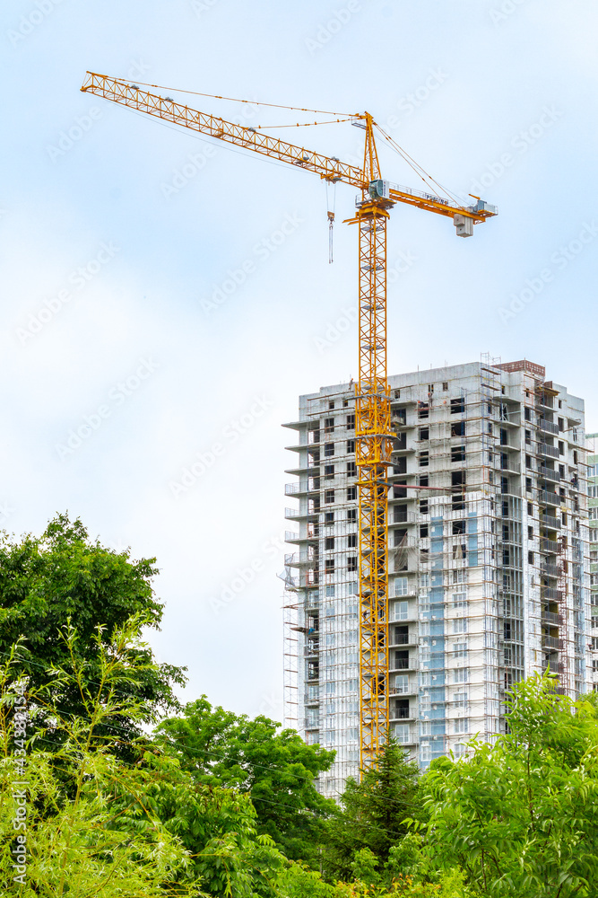 Tower crane on the background of a high-rise building under construction.