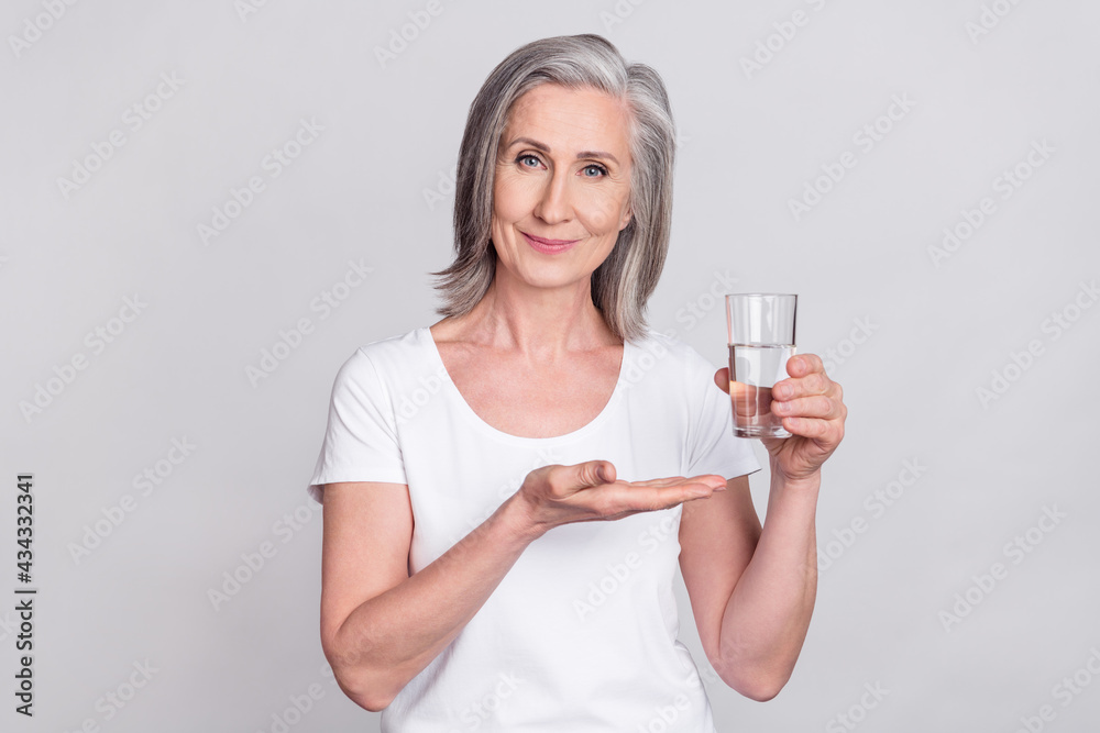 Photo of elderly woman happy positive smile drink water drugs vitamins isolated over grey color background Photo of elderly woman happy positive smile drink water drugs vitamins isolated over grey color background