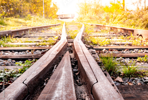 Old abandoned railway with rusty rails in the summer during evening sunset.
