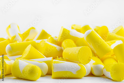 Macro shots of multiple earplugs in yellow and white for noise protection, isolated on white background.