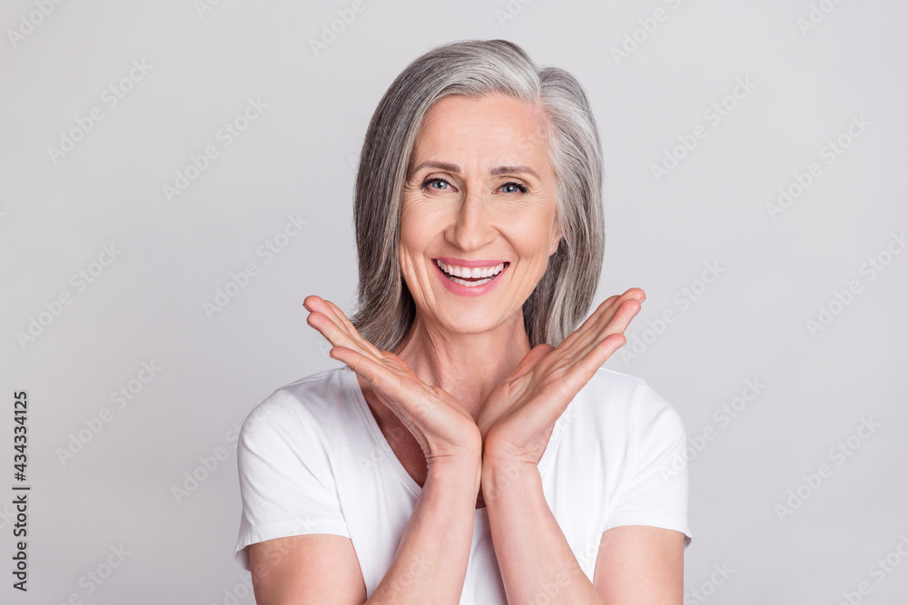 Photo of cheerful aged woman happy positive toothy smile wear t-shirt isolated over grey color background Photo of cheerful aged woman happy positive toothy smile wear t-shirt isolated over grey color background