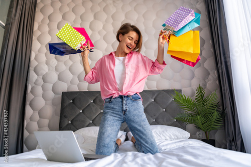 pretty happy woman jumping on bed at homeshopping online photo