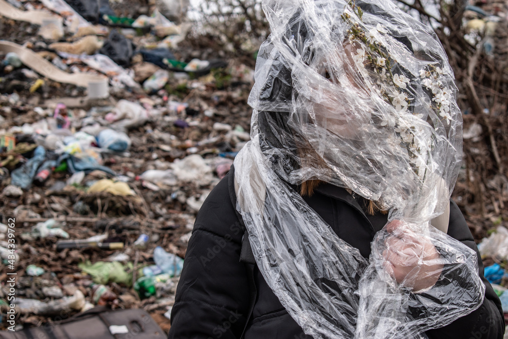 Man wrapped in a plastic bag on a garbage dump. Environment protection