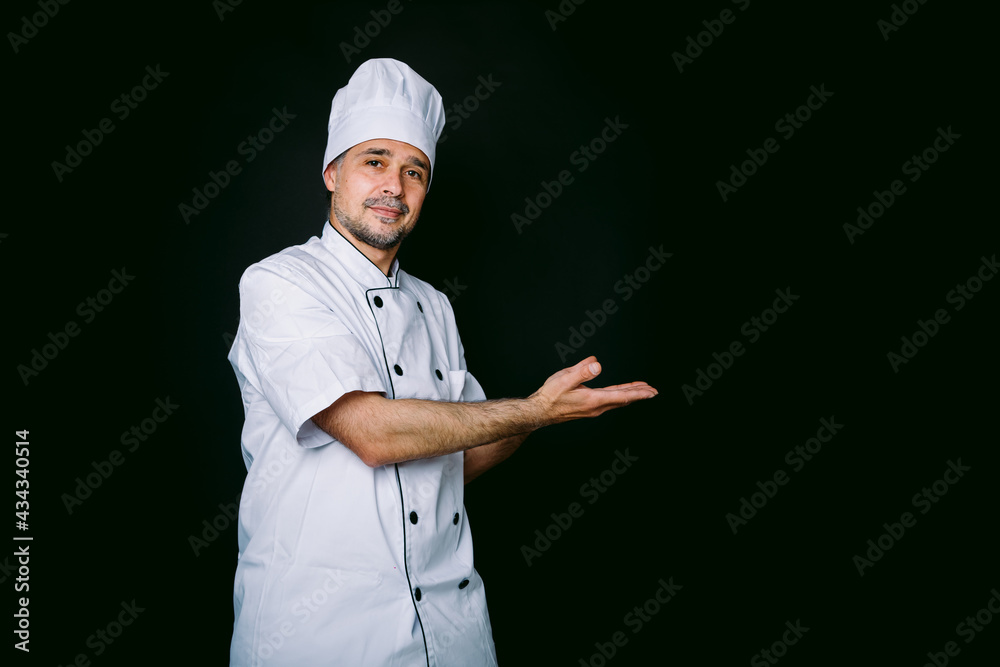 Chef cook wearing jacket and kitchen hat pointing right on black background Chef cook wearing jacket and kitchen hat pointing right on black background