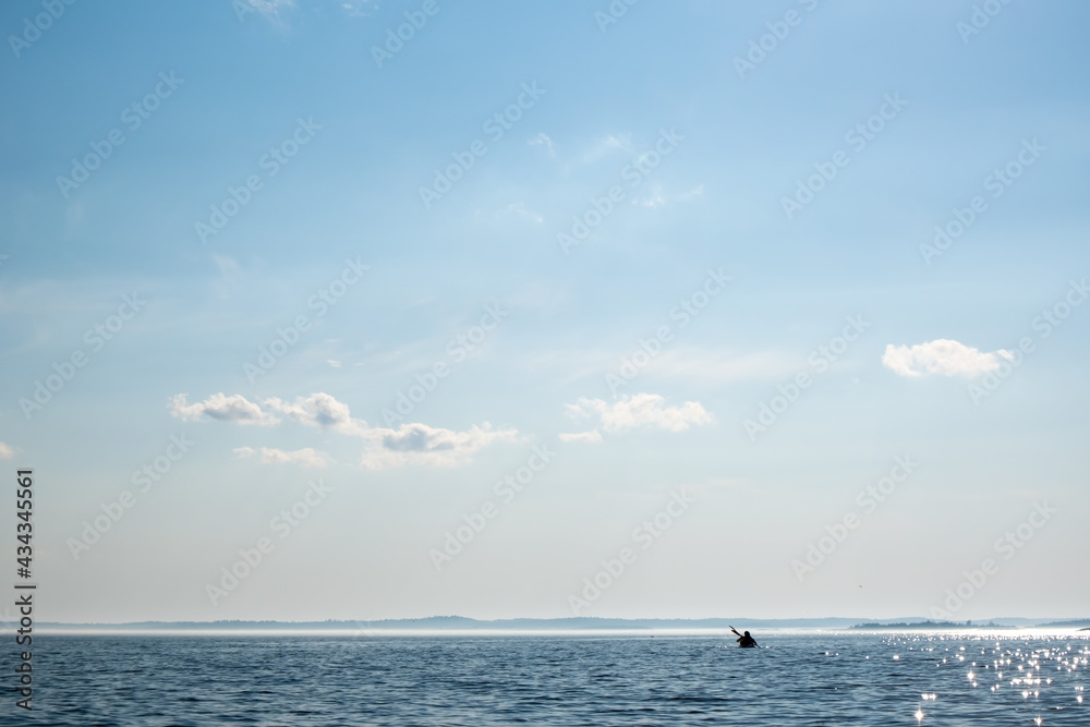 Silhouette of a kayak with tourists floating on the lake against the horizon. Active rest. Beautiful landscape.
