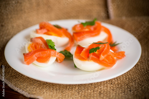 halves of boiled eggs with pieces of salted salmon