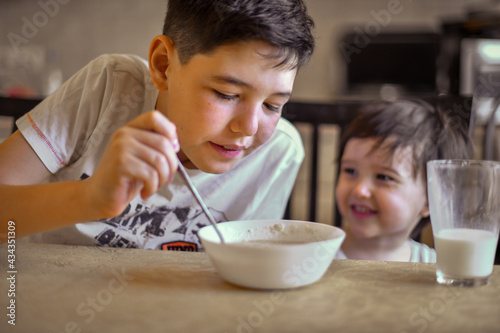 the older brother feeds the younger one porridge