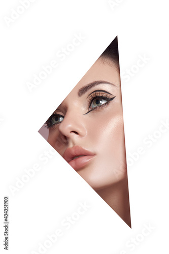 Beauty makeup women, eye brows eyelashes and lips in a triangular hole paper white background. Professional beauty makeup, place for text, copy space © angel_nt