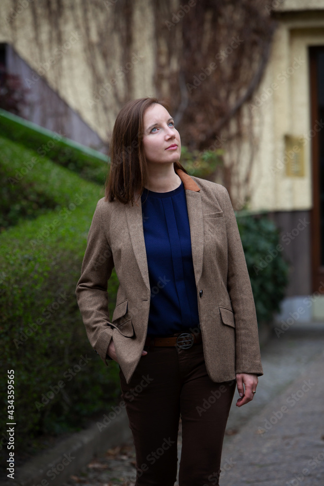 portrait young brunette woman in brown suit standing in front of building