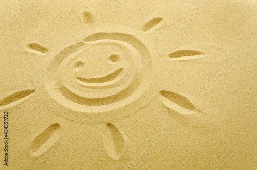 face of smiling sun drawn in sand, empty space