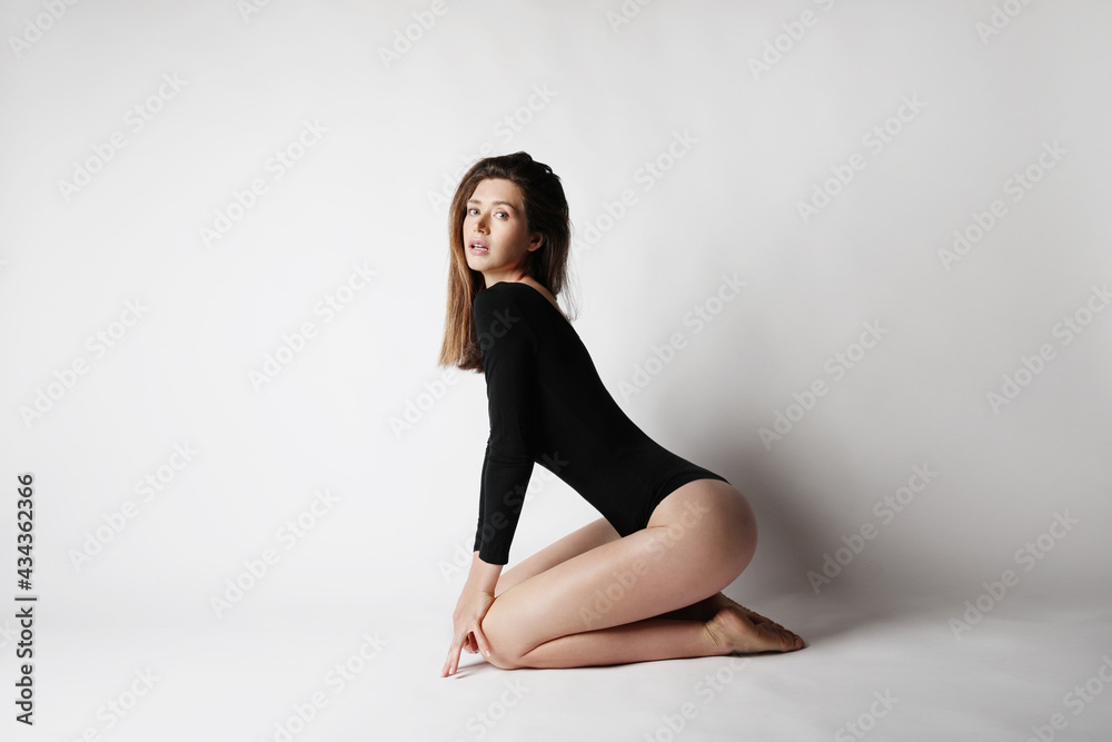 Young caucasian fitness woman, wears black body, posing at the studio.