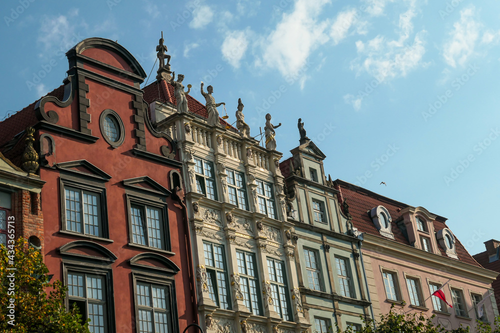 Fototapeta premium A close up of the facades of tall building in the middle of Old Town in Gdansk, Poland. The buildings have many bright colors, they are richly decorated. City tour. Clear day.