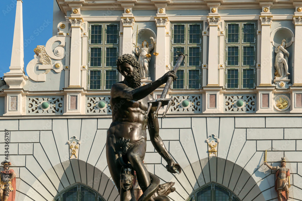 Obraz premium The Neptune's Fountain in Old Town of Gdansk, Poland. The fountain is located in the central point. Town Hall building in the back. City tour. Clear and bright day.