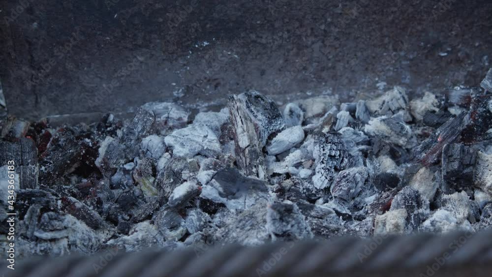 Smouldering embers close-up. From them comes a small smoke and flies ash. A slight red flicker is visible Smouldering embers close-up. From them comes a small smoke and flies ash. A slight red flicker is visible
