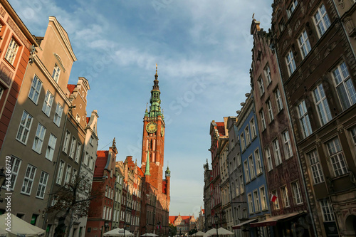 A close up of the facades of tall building in the middle of Old Town in Gdansk, Poland. The buildings have many bright colors, they are richly decorated. High tower of Town Hall. City tour. Clear day.