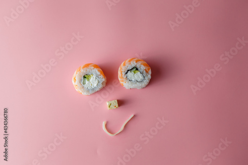 Sushi roll and noodle emoticon. Smiling face on a pink background. The concept of good mood and proper nutrition. Food is enjoyable
