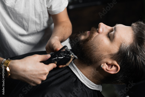 Trimming the beard with a shaving machine. Advertising for barbershop and men's beauty salon