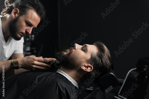 Trimming the beard with a shaving machine. Advertising for barbershop and men's beauty salon photo
