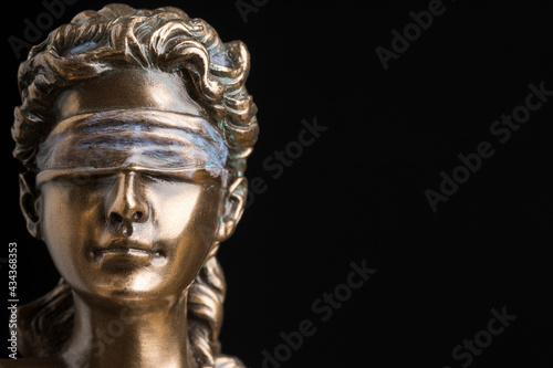 Portrait of the blindfolded goddess of justice Themis isolated on black background with copy space, as a legal concept