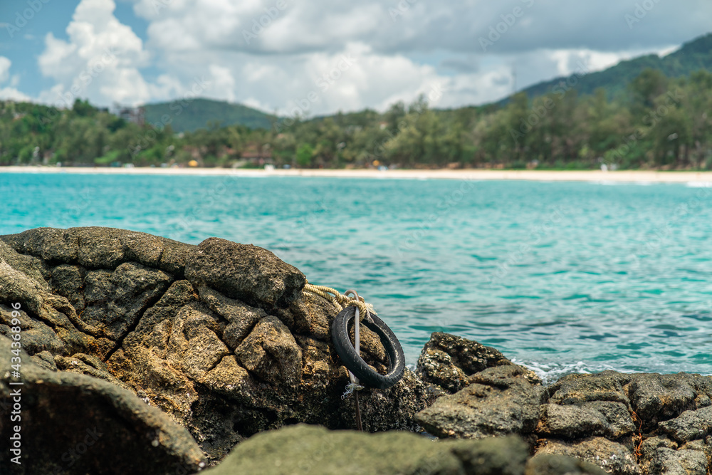 Rubber wheel tied to corals stone against the backdrop of a turquoise bay Rubber wheel tied to corals stone against the backdrop of a turquoise bay