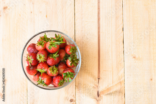 Strawberry in glass bowl on wooden background 