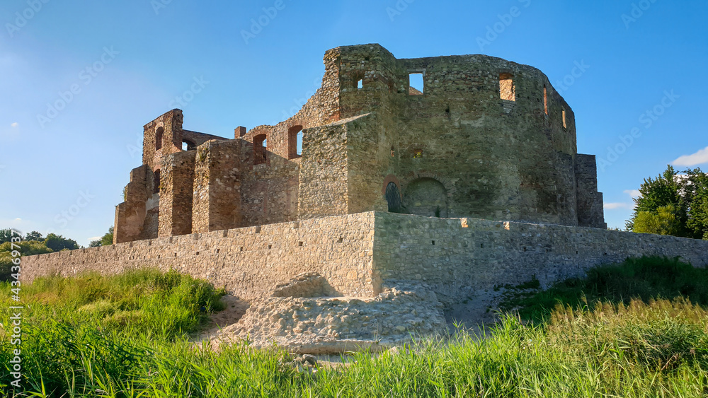 The ruins of Castle of Bishops in Siewierz, Poland. There is a wooden bridge leading to the castle. The castle is being under renovation. Restoring the old buildings. Clear, blue sky.