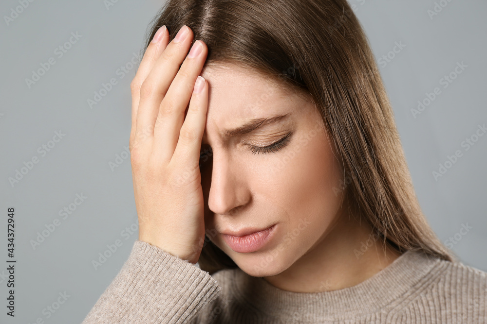 Young woman suffering from migraine on grey background Young woman suffering from migraine on grey background