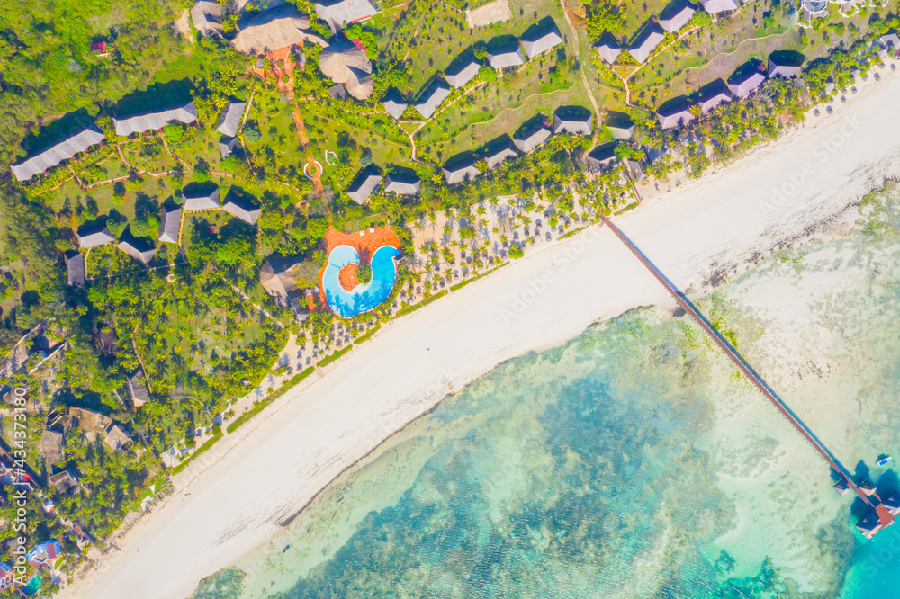Aerial view of beautiful hotel in Indian ocean at sunset in summer. Zanzibar, Africa. Top view. Landscape with wooden hotel on the sea, azure water, sandy beach, green trees, boat. Luxury resort