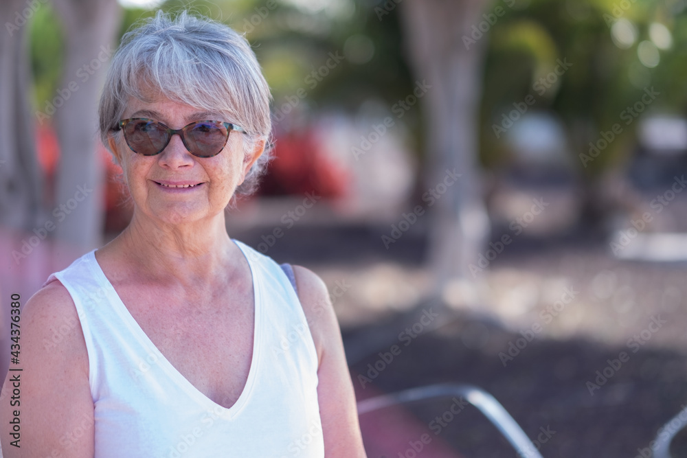 Beautiful senior woman sitting in outdoor public park smiling Beautiful senior woman sitting in outdoor public park smiling
