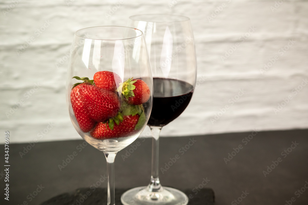 Ripe juicy red beautiful strawberry close-up is an appetizing fresh snack paired with glass of red wine Ripe juicy red beautiful strawberry close-up is an appetizing fresh snack paired with glass of red wine