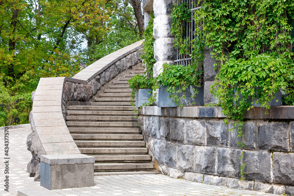 Massive stone stairs around the old castle in a green park.