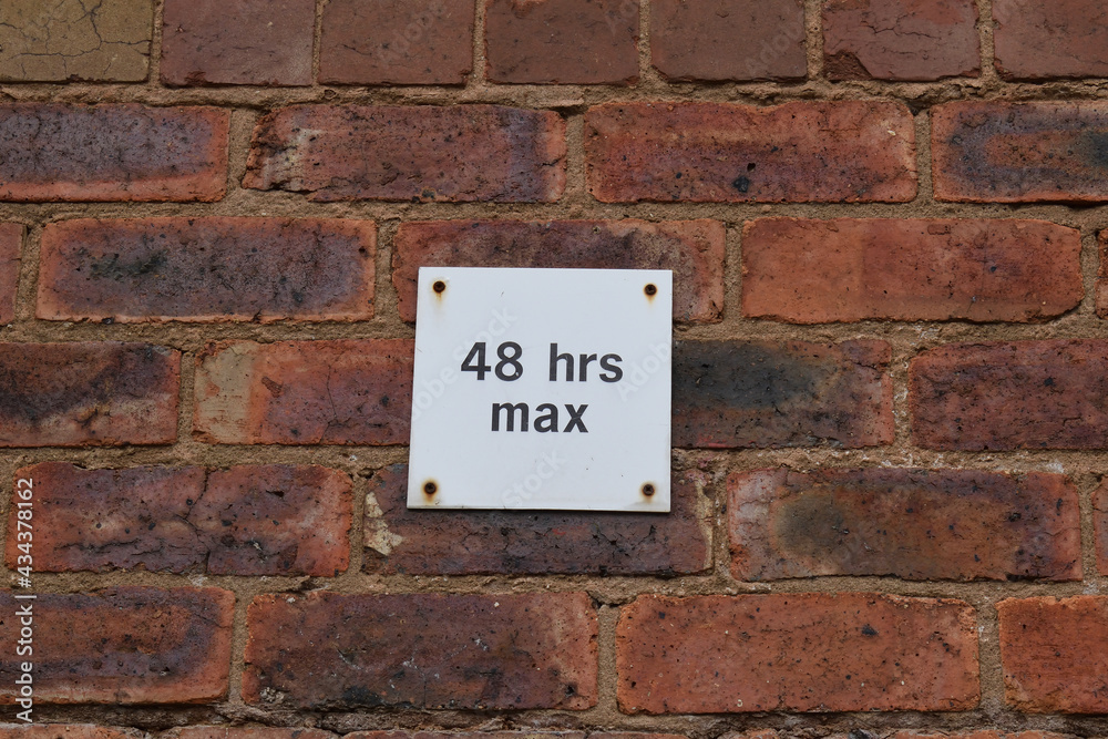 White Metal Parking Sign with Time Limit fixed to Old Brick Wall in Car Park White Metal Parking Sign with Time Limit fixed to Old Brick Wall in Car Park