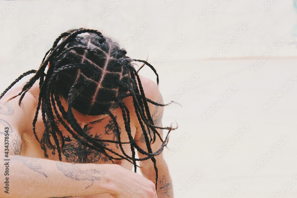 Portrait of young man shirtless with tattoos on skin and tight hair braids , hairstyle / style  - obrazy, fototapety, plakaty 