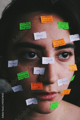 Closeup portrait of young woman with price tags on face with texts as stereotype social norms / taboos / labels / gender roles, an artistic image about womens rights photo