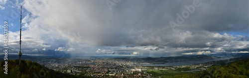 Panorama shot from Uetliberg on Zurich with cloudy skies and green forests with a beautiful rainbow  © Ben T.