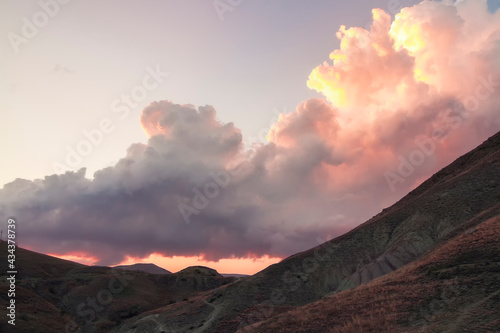 A big cloud over mountains at sunset in an autumn evening